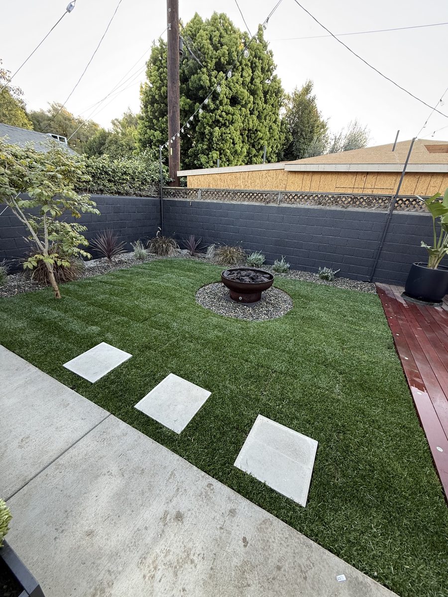 Modern minimalist backyard with turf, stepping stones and fire bowl